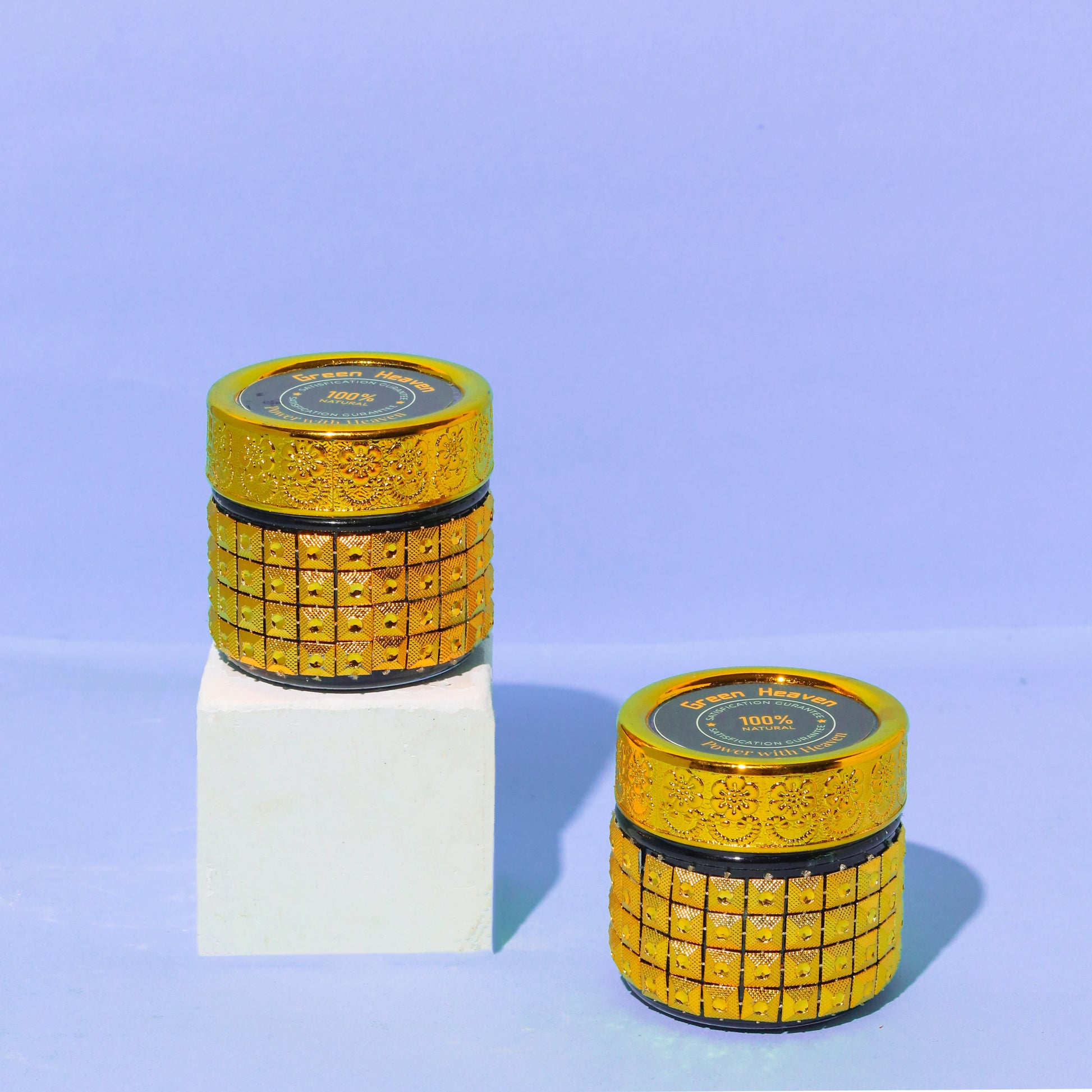 Two gold cylindrical containers with decorative patterns on a light blue background