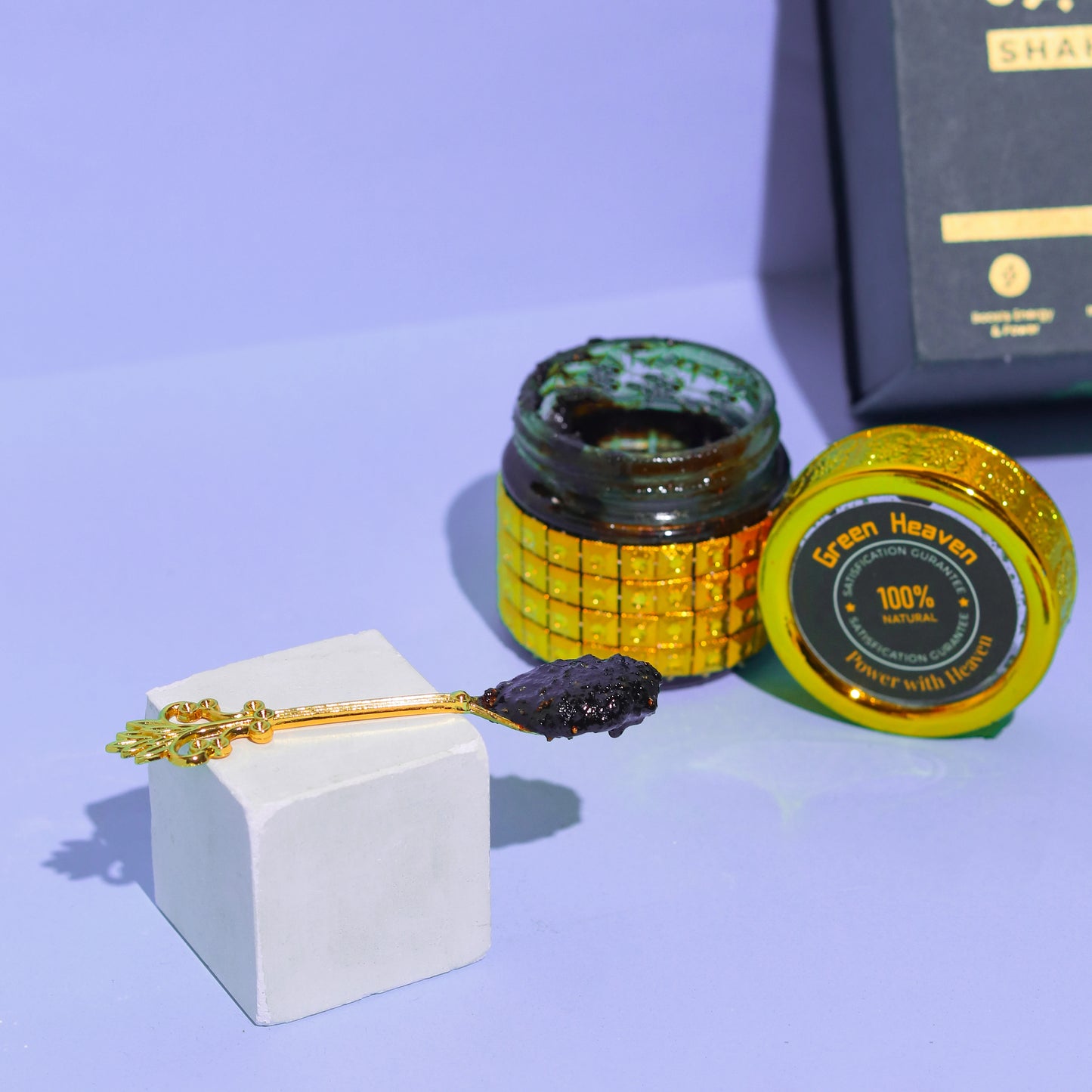 Open jar of green paste with a spoonful on a white block against a purple background