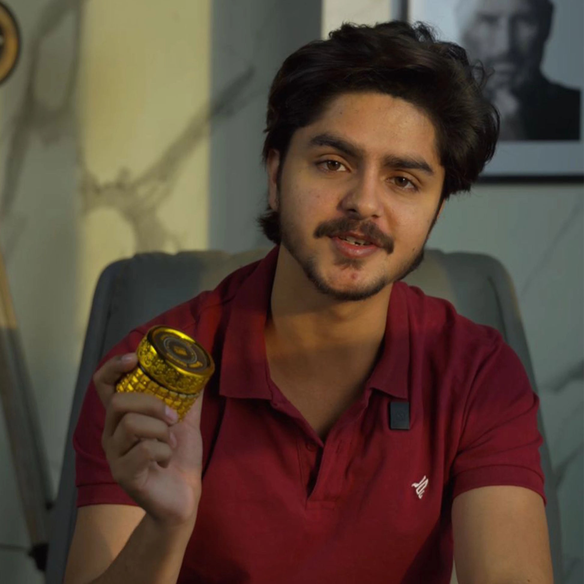 Man in red shirt holding a gold object indoors